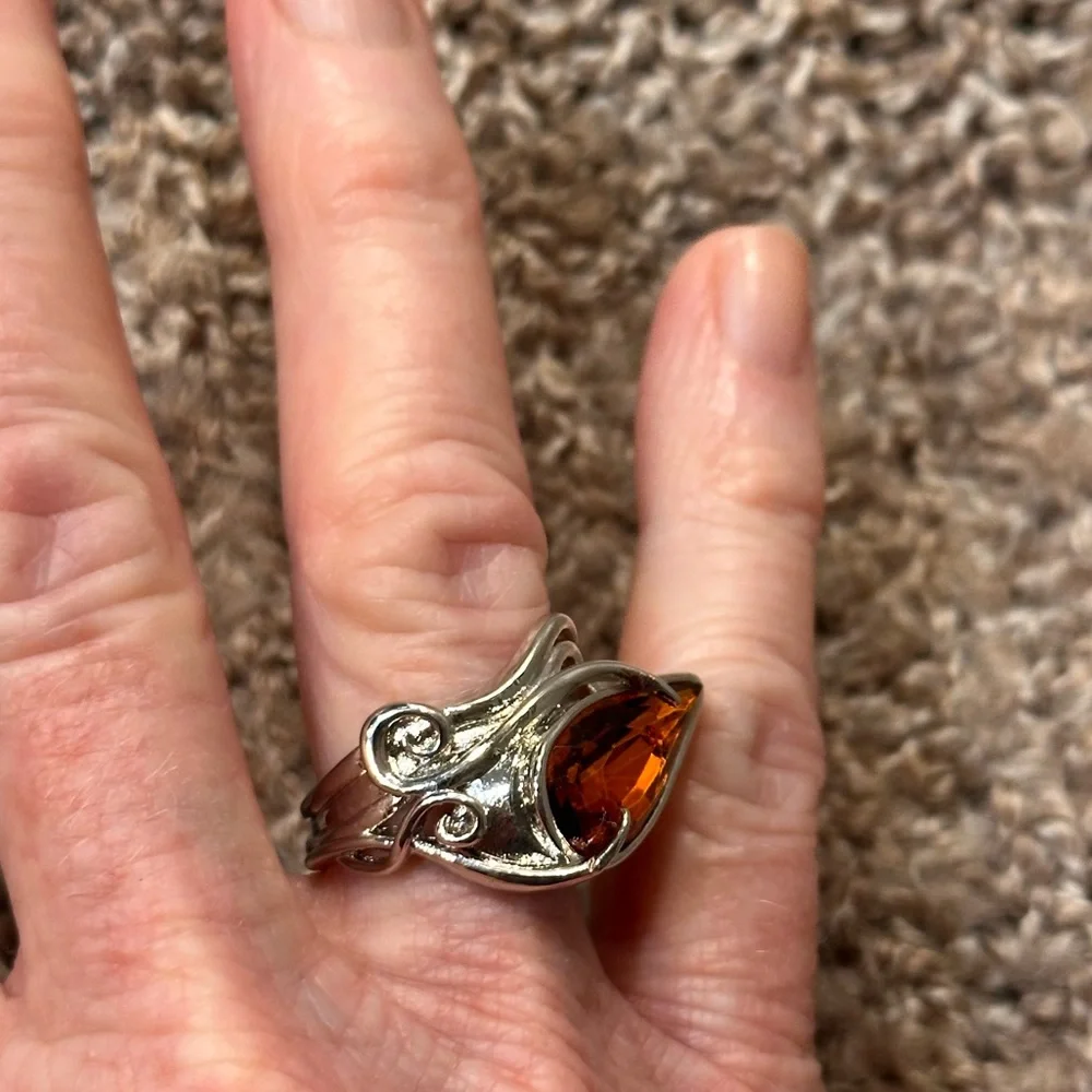 Ring in silver metal intricate with teardrop shaped amber color stone
